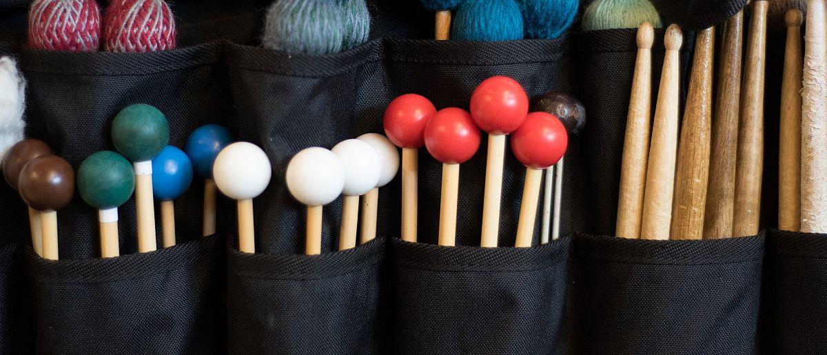 Image of multiple and various colored drumming mallets.